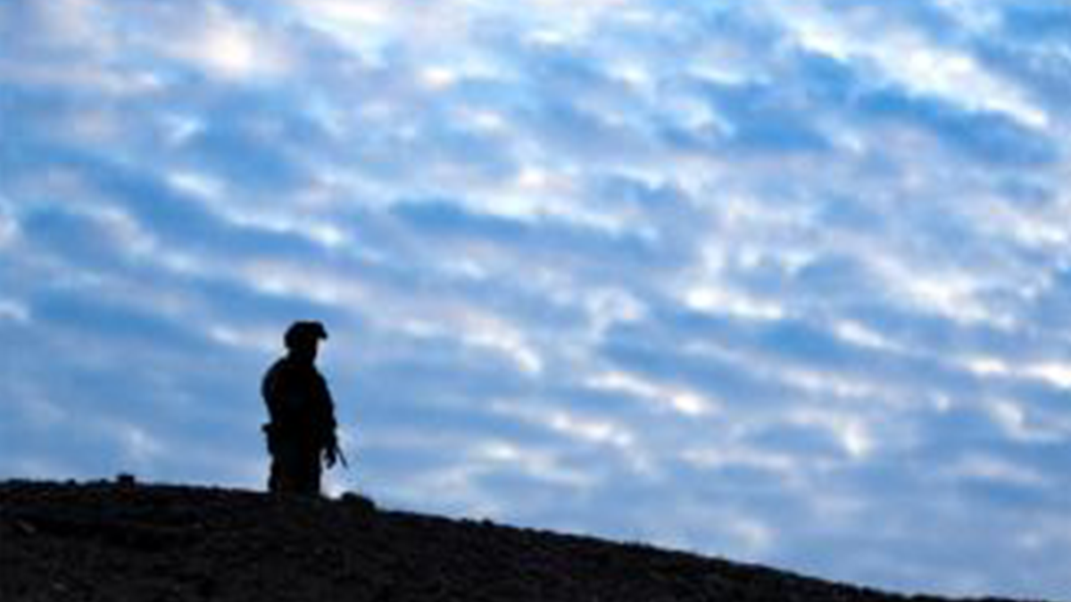 A soldier stands on a ridgeline in Afghanistan