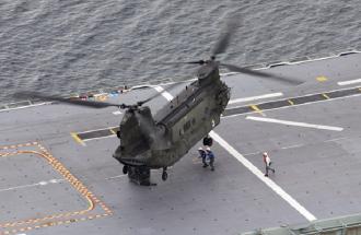 A CH-47D Chinook about to hook up an external load on board a Navy LHD.