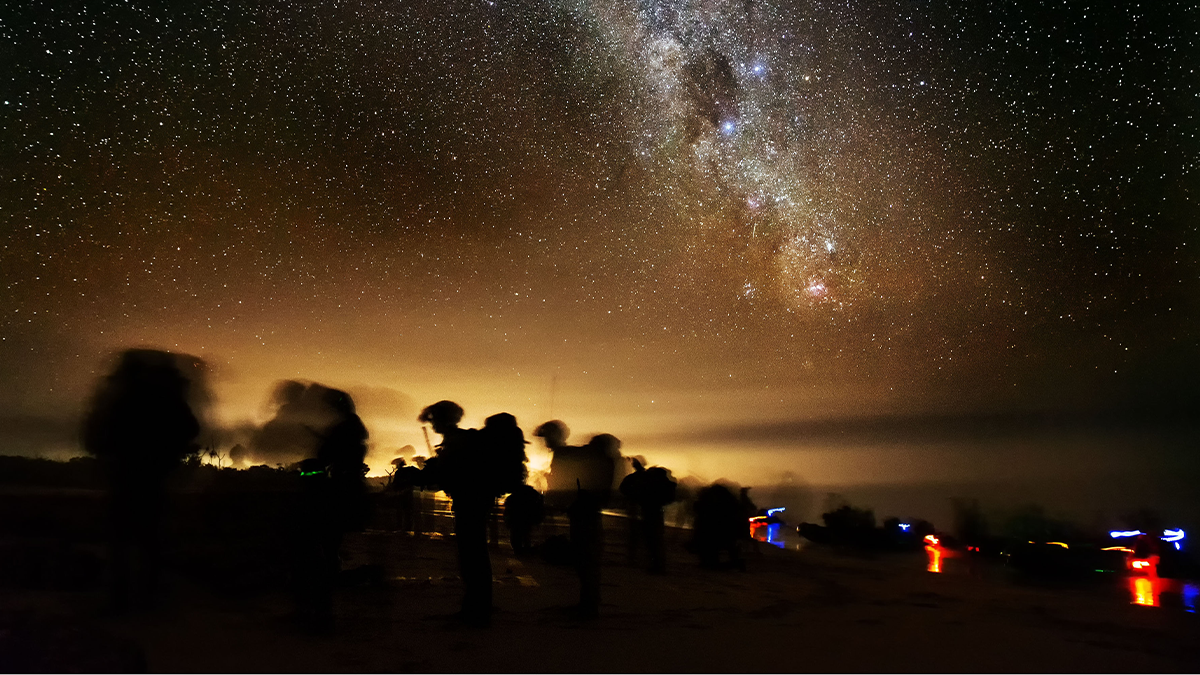 Silhouette soldiers blurred in motion under starry sky