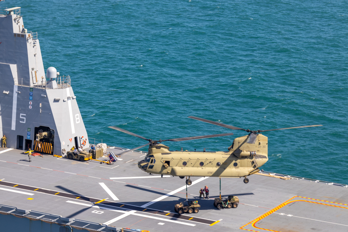 An Australian Army CH-47 Chinook lifts two All Terrain Vehicles from the flight deck of HMAS Adelaide during Exercise Sea Explorer 2022.