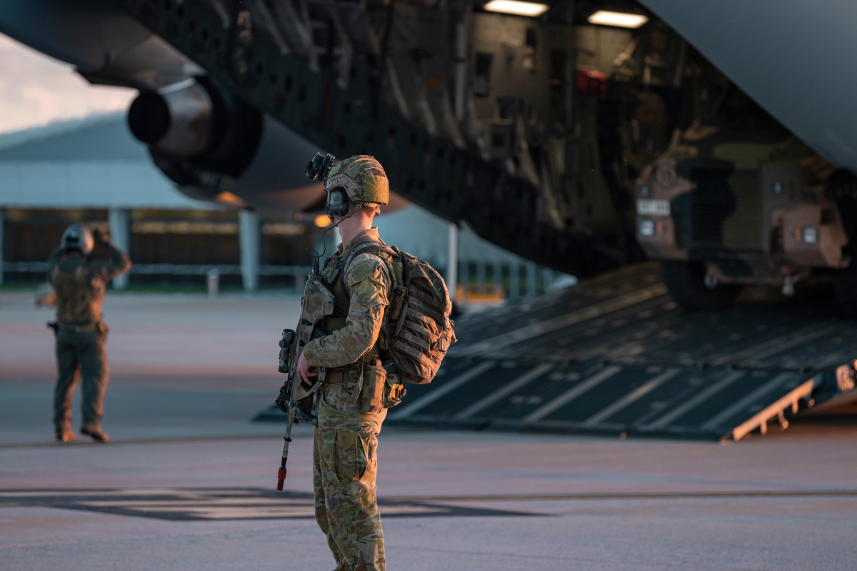 A Royal Australian Air Force Airfield Defence Guard from No. 2 Security Forces Squadron secures Wellcamp Airport, Toowoomba as Australian Army soldiers from the 8th/9th Battalion, The Royal Australian Regiment, dismount a Royal Australian Air Force C-17A Globemaster apart of Exercise Ram Stallion.