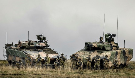 Two IFV Vehicles next to each other with soldiers in frotn of them