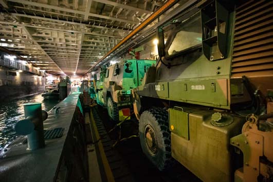 Australian Arrmy Bushmaster PMVs await loading onto landing craft inside HMAS Canberra, a Landing Helicopter Dock of the Royal Australian Navy.