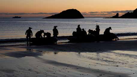 Soldiers prepare to evacuate a beach on boats at night.