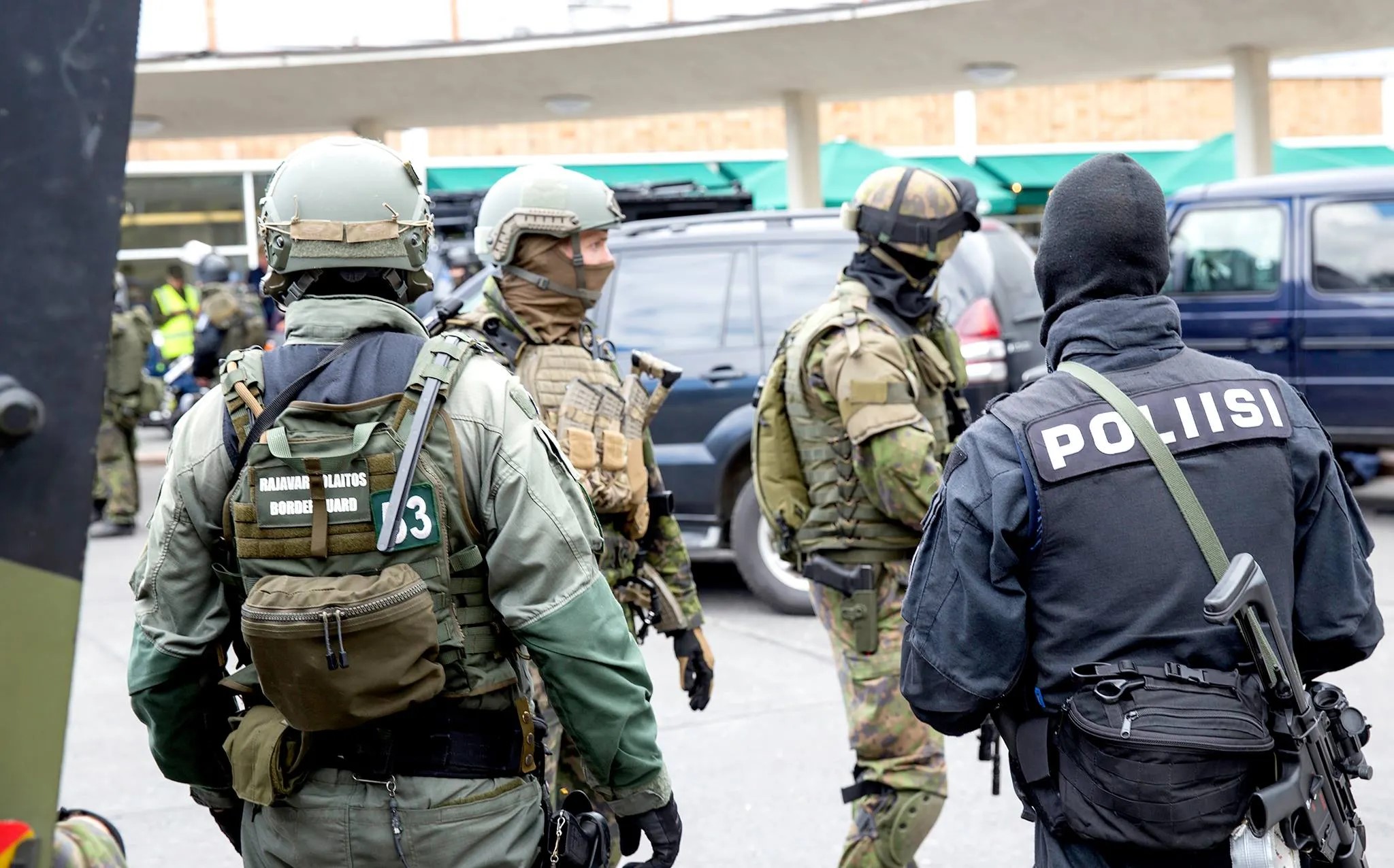Four tactically dressed Finnish Police in a car park.