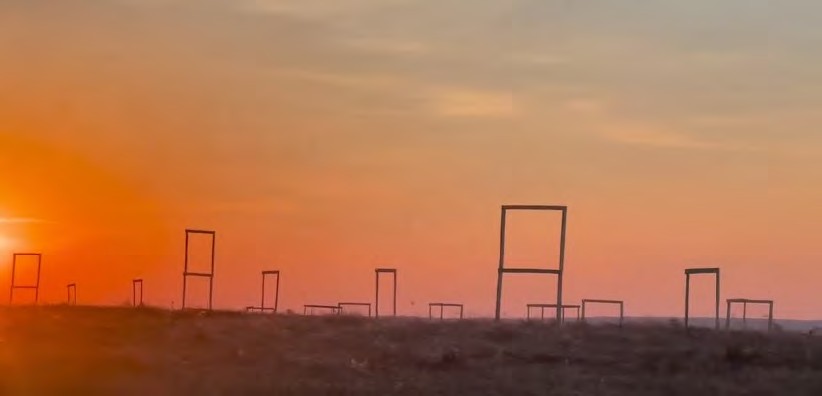 A field at sunset with rectangular frames standing up from the ground.