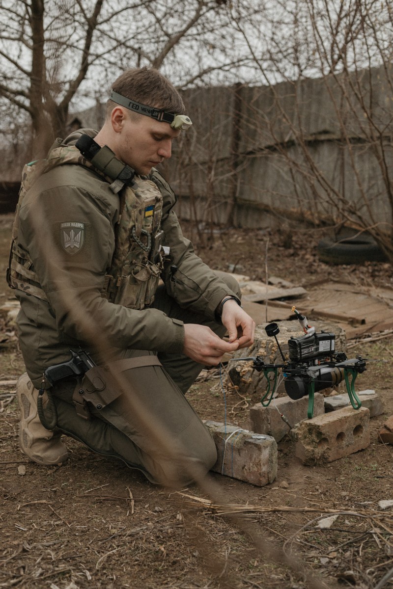 Soldier kneeling and preparing a drone.