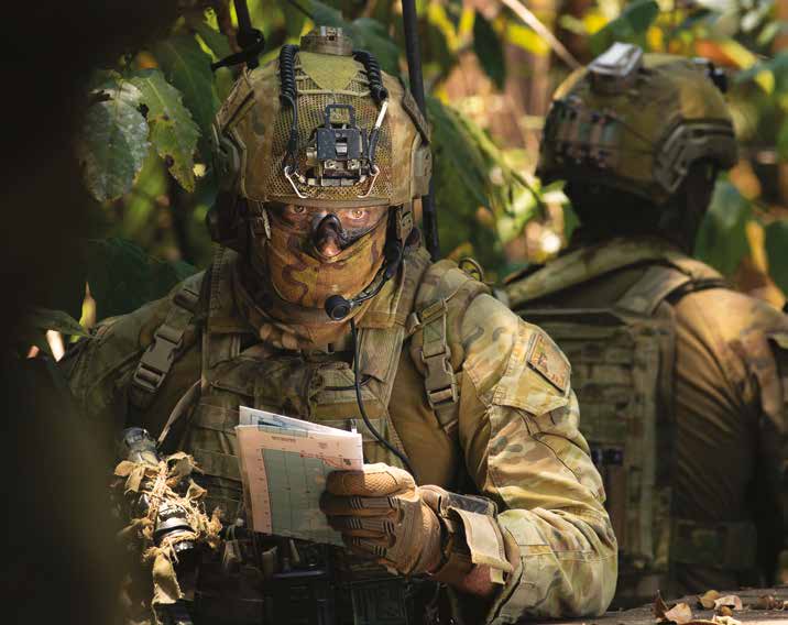 A soldier out field looking at their map.