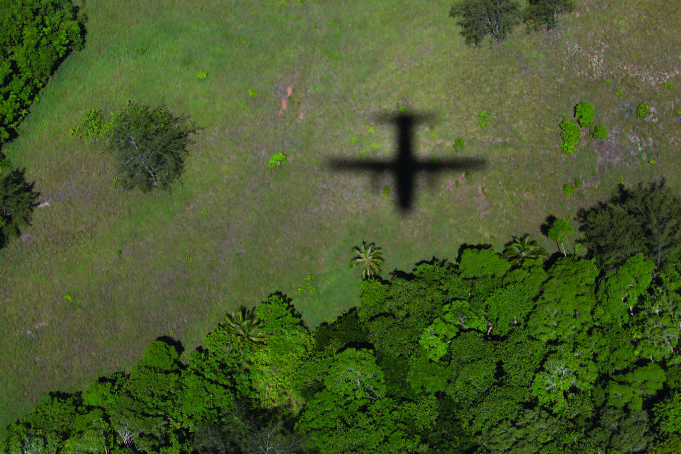 Shadow of a plane on the land as it flies overhead.