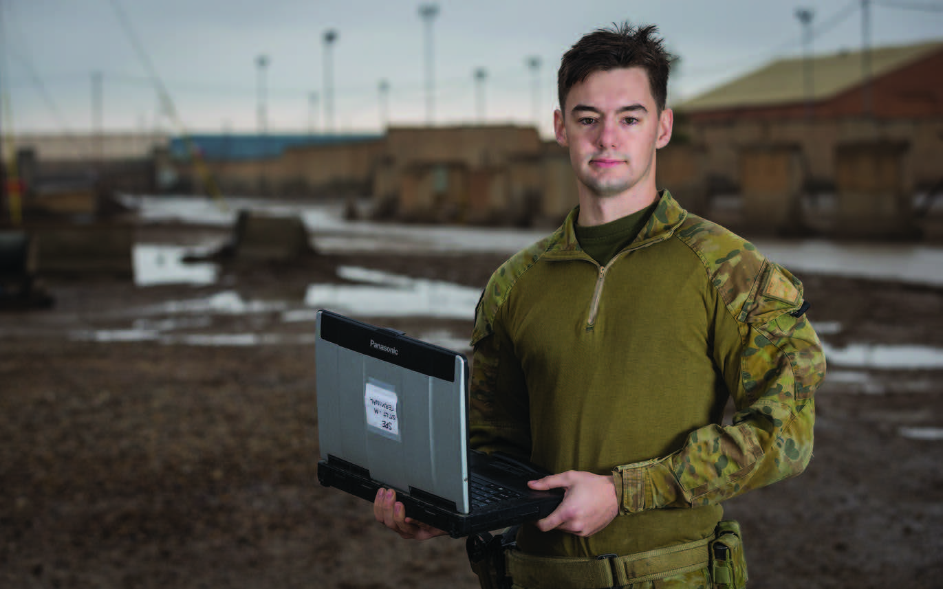 A Soldier stands with a field laptop in his hands while on Operation.