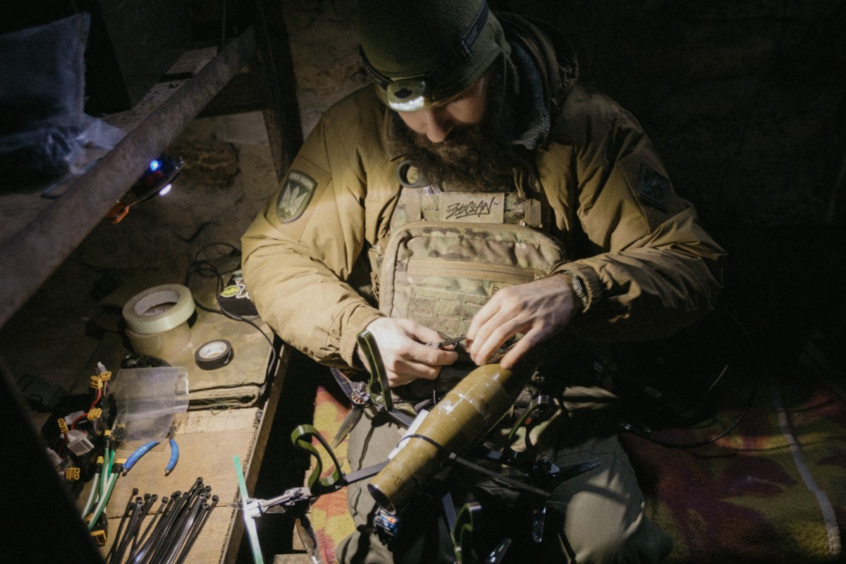 Soldier conducting technical work in a dark workshop by lamp light.