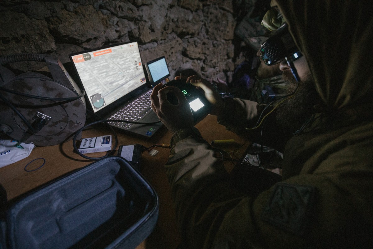 Soldier in underground location using a laptop, a phone and a tablet.