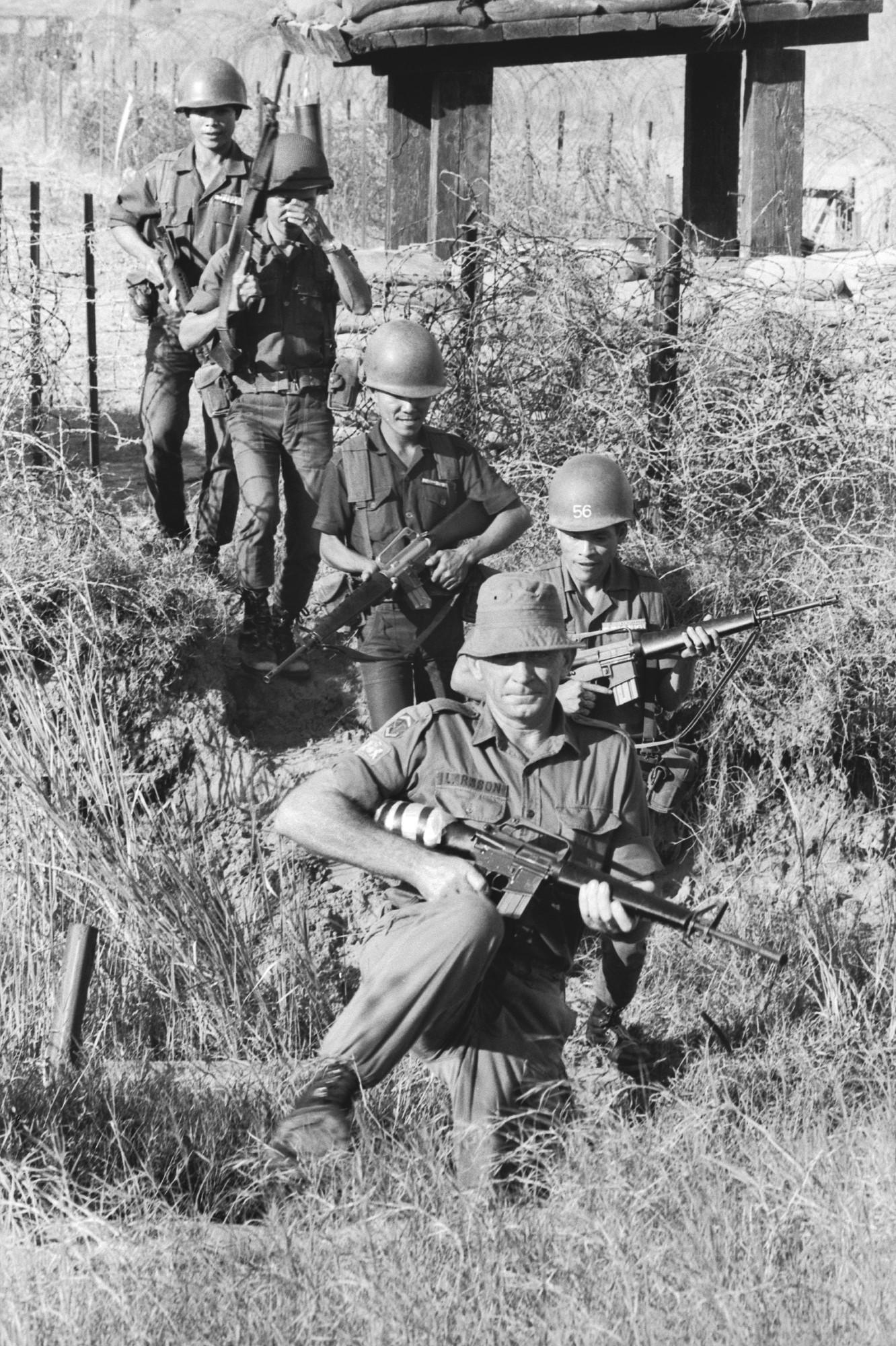 AATTV instructor, Warrant Officer Class 1 Ned Larsson, leads Vietnamese students through a wire perimeter to illustrate night operation techniques, Dong Tam, South Vietnam, November 1971. (Source: Australian War Memorial)