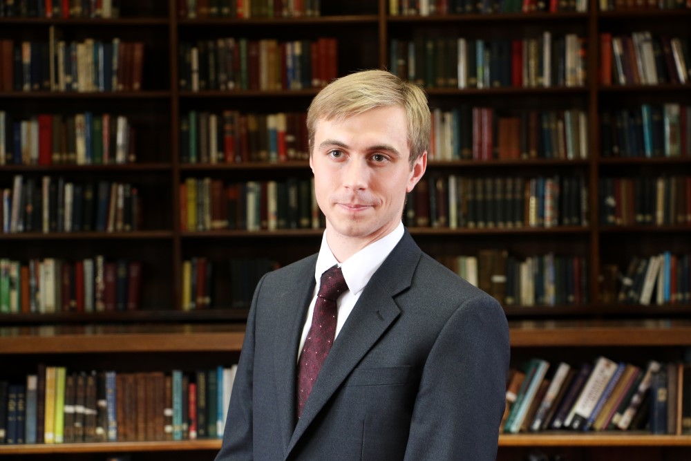 Profile picture of Dr Jack Watling with library in the background.