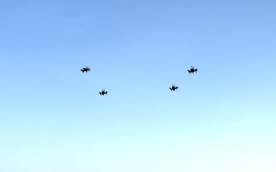 Four drones swarming with the blue sky as the background