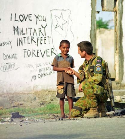 A soldier of the Australian-led International Force East Timor - INTERFET - makes friends with a local boy.