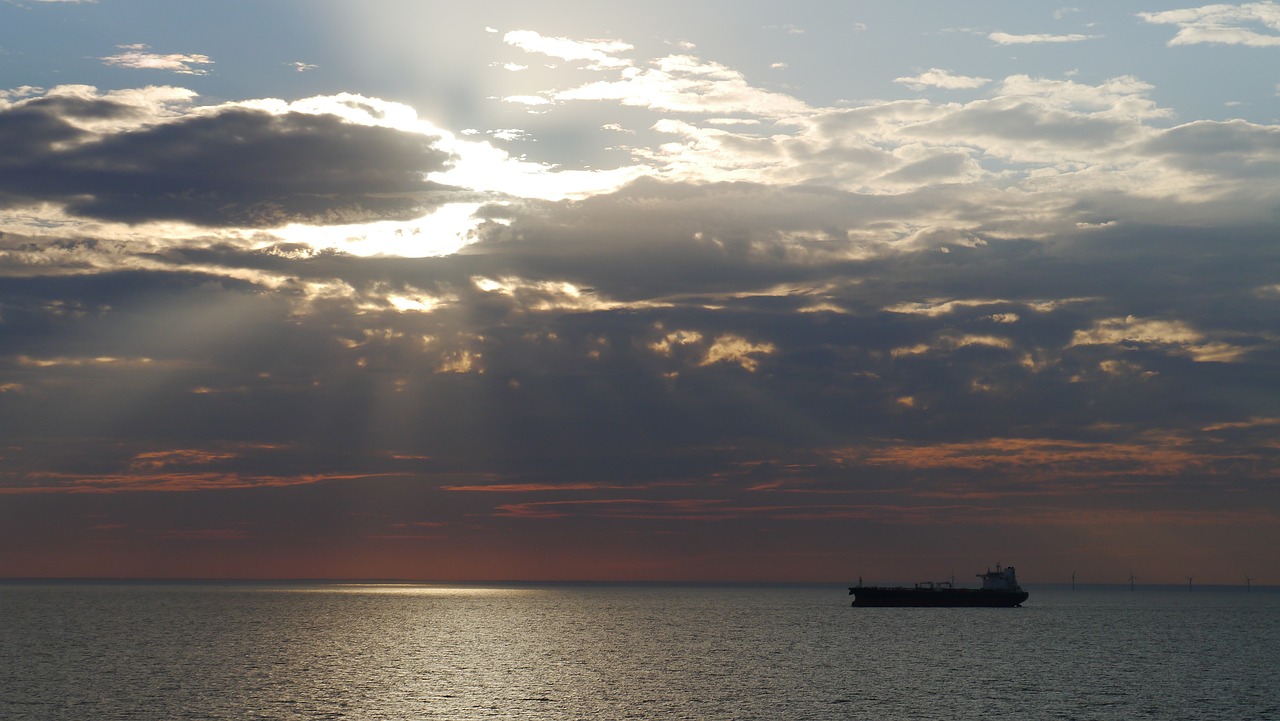 Oil tanker on calm waters in the distance with the sunset in the top two thirds of the image. Source: [10:55 pm] Matthew Struthers JACOBS (Guest) Pixabay user: Lingualpirat-Glenn (https://pixabay.com/users/lingualpirat-glenn-9811466)