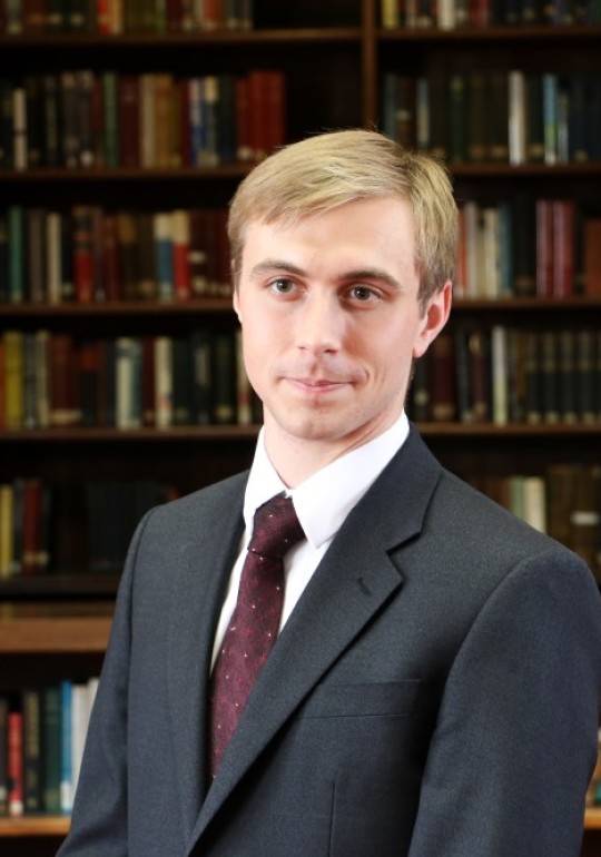 Profile picture of Dr Jack Watling with library in the background.