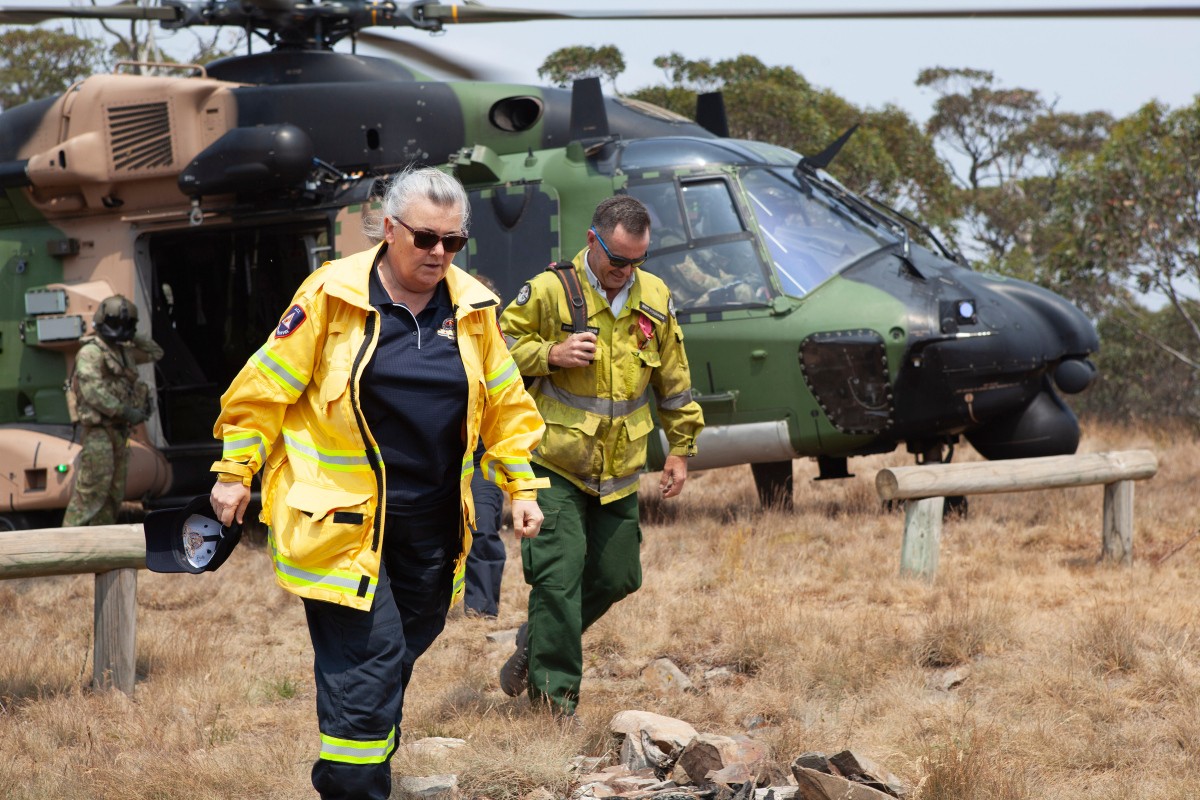 ACT Emergency Services Agency Commissioner, Ms. Georgeina Whelan and Brett McNamara, the Area Manager for the Namadgi National Park disembark from an MRH-90 Taipan helicopter at Mt Ginini.