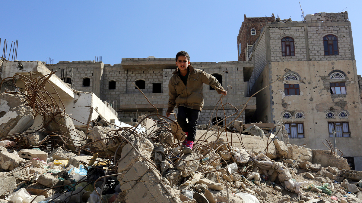 Child standing on city rubble.