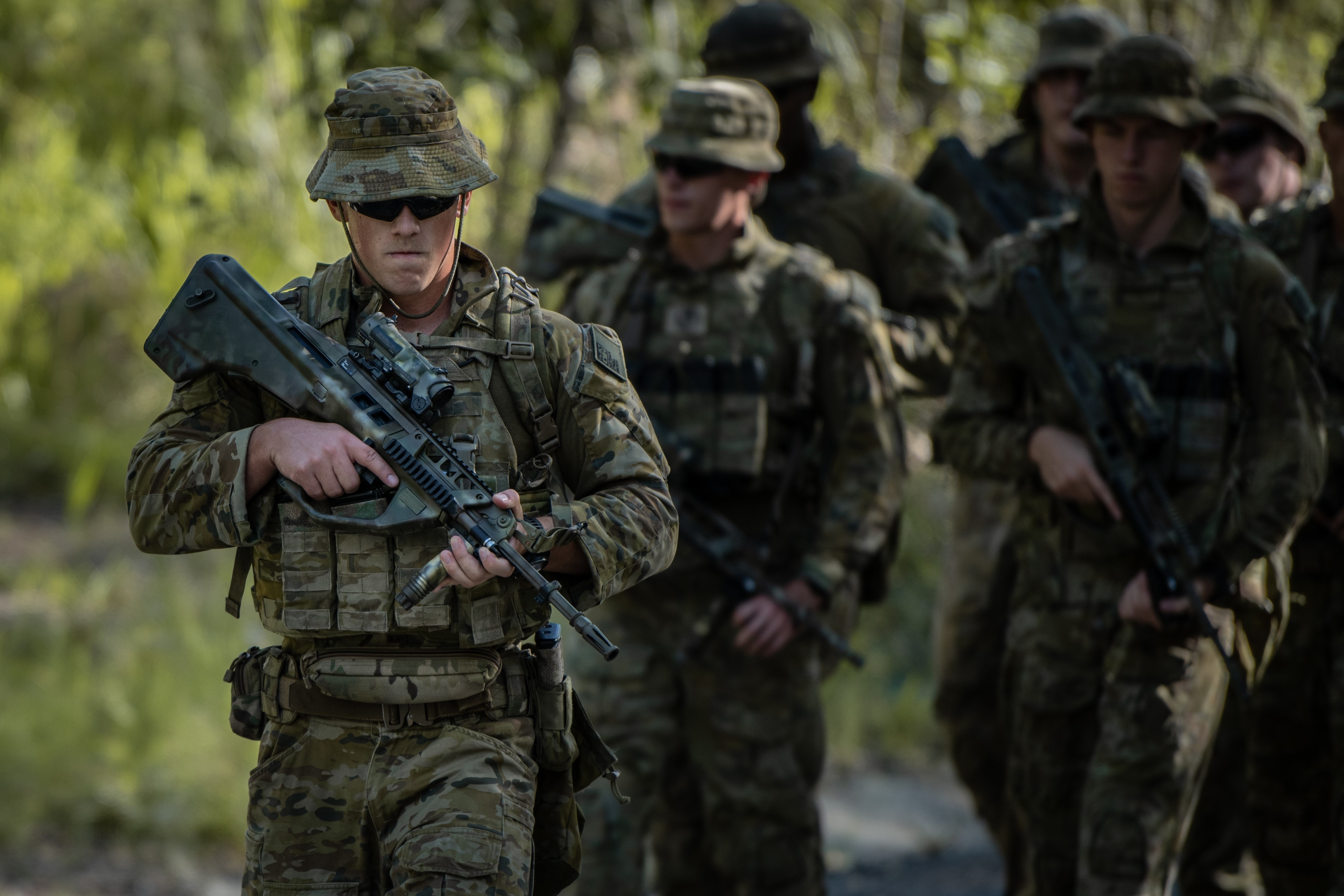 Armed soldiers walking with blurred scrub in the background