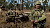 Soldier drone operator on right, wheeled drone on left; left side of image has honeycomb overlay