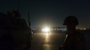 Soldier in foreground with night vision and aircraft in background with lights glaring