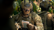 Soldier, waist up, reading a map in jungle environment