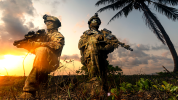 Soldiesr on a beach kneeling, sunset in the background