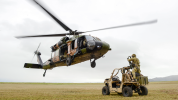 Blackhawk helicopter in air just above and in front of a buggy on a plain