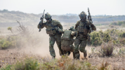 Two soldiers carrying another soldier by arms