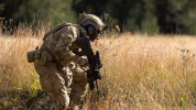 Soldier crouched in dry waist high grass