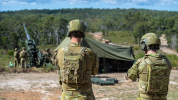 Two soldiers in foreground watching gunnery team