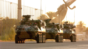 Three APCs driving towards us on a road with Iraq's Victory Arch in the background
