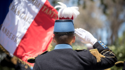 French Military member from behind saluting with a French coloured flag in the background