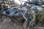An Australian Army soldier runs past an Australian Light Armoured Vehicle on Forrest Beach, Queensland, as part of an amphibious assault activity, during Exercise Talisman Sabre 2021.
