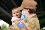 Australian Army officer Captain Sarah Kelly, Public Affairs Officer deployed on Pacific Partnership 2022, holds a child from the local community at Macarascas Elementary School, Palawan, Philippines.