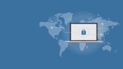 Computer screen in foreground displaying a padlock with image of flattened earth in background on a blue background