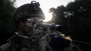 Australian soldier looking down his weapon, with full gear on.