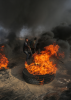 A burning tyre in Gaza, with a man placing a pole inside the burning tyre