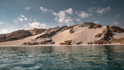 Hilly sandy shoreline viewed from water level away from shore