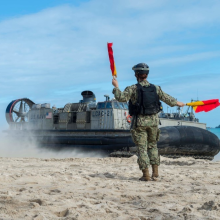 Logistics Specialist Seaman Courtney Lucarelli, from Youngstown, Ohio, directs landing craft air cushion (LCAC) 21, assigned to Naval Beach Unit 7, to depart a beach as a part of a large-scale amphibious assault training exercise during Talisman Saber 17. (U.S. Navy photo by Mass Communication Specialist 3rd Class Sarah Myers/Released)