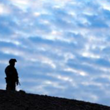 A soldier stands on a ridgeline in Afghanistan