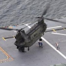 A CH-47D Chinook about to hook up an external load on board a Navy LHD.