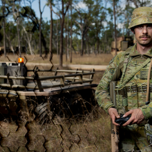 Soldier drone operator on right, wheeled drone on left; left side of image has honeycomb overlay