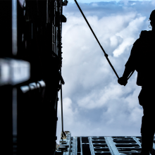 Soldier silhouette on rear ramp of aircraft with clouds in background