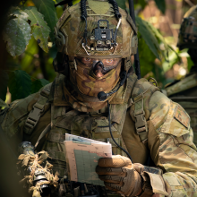 Soldier, waist up, reading a map in jungle environment