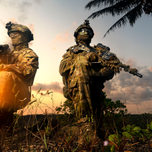 Soldiesr on a beach kneeling, sunset in the background