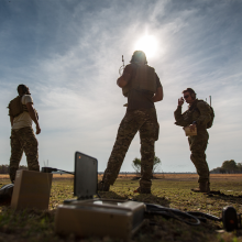 Three soldiers on a field with sun shining behind them