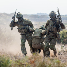 Two soldiers carrying another soldier by arms